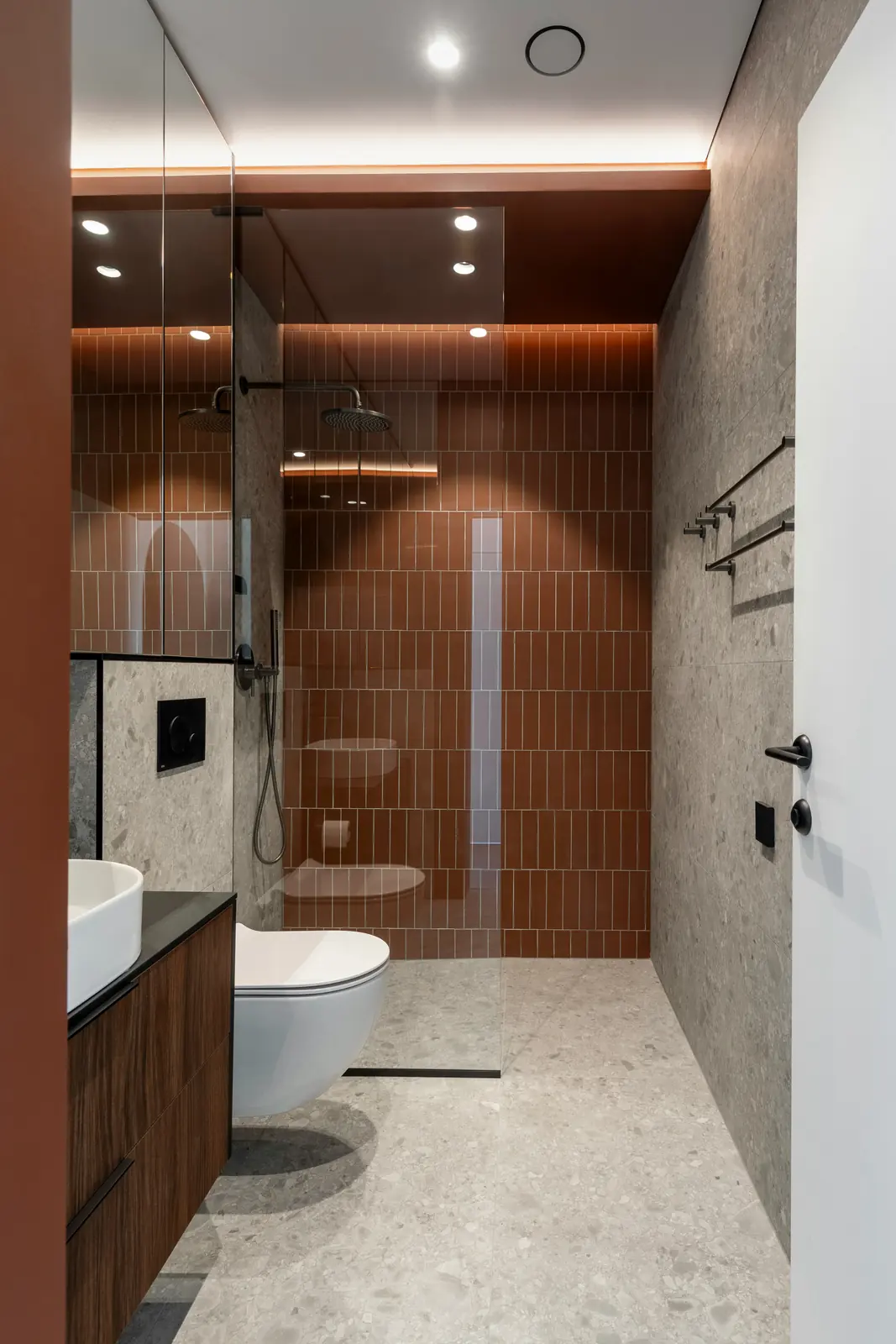 Modern bathroom with a terracotta tiled walk-in shower, dark wood vanity, and stone floor