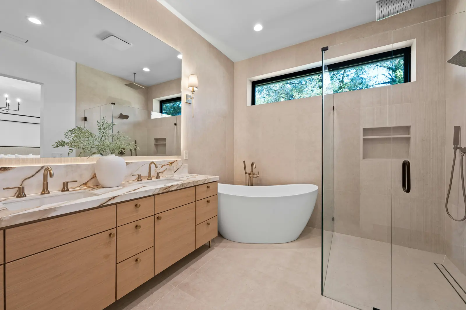 Finished luxury bathroom with oak double vanity, marble countertop, freestanding tub, and glass walk-in shower