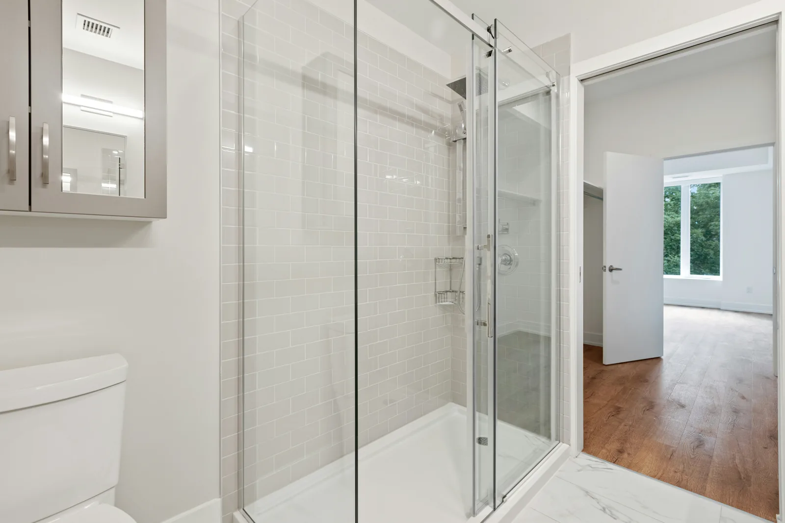 Frameless glass walk-in shower with white subway tile in a bright bathroom